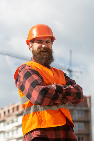 Portrait of worker man at construction site. Improvement and renovation. Brutal man builder. Engineer builder in uniform.の写真素材