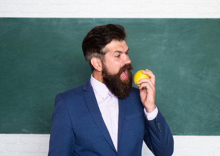 Portrait of a funny teacher or professor near blackboard. Thinking serious mature teacher. Mature professor, middle aged teacher, bearded man.の写真素材