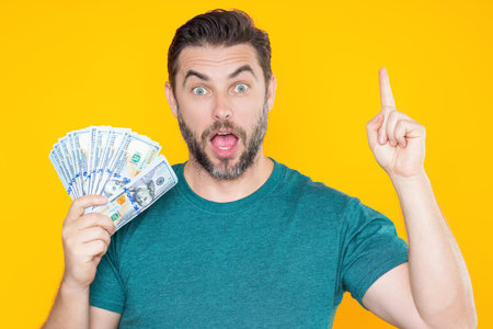 Man hold money on yellow studio isolated background. Rich man with money dollar bills. Successful...