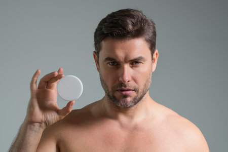 Man with cosmetic cream. Male spa model applying skin care cream product. Morning skincare cream, lifting and anti-aging wrinkle effect. Skin care. Man with perfect soft skin. Beauty cosmetic product.の写真素材