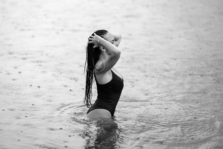 Beautiful model relaxing at nature. Sexy model on nature at summer vacation. Beautiful girl in a swimsuit posing sexy in the water. Exotic country travel and rest concept. Slim figure and sexy body.の写真素材