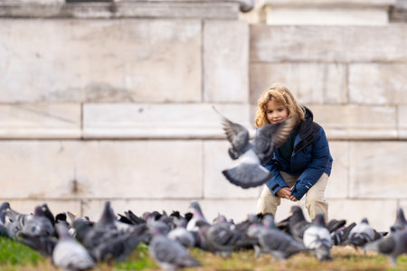 Carefree child chasing birds on autumn day. Child run for pigeons. Carefree kids concept. Happy childhood. A child chases pigeons in park. Carefree Child playing with doves. Carefree Kid run pigeons.の写真素材
