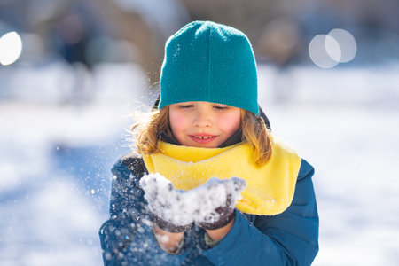 Kids face in snow. Happy Child playing with Snowball. Child in winter clothes play with snow. Winter children play with snow. Portrait of cute child in snow. Winter kids face. Boy play snowball.の写真素材