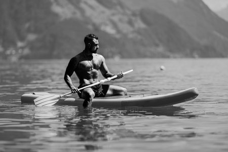 Muscular man with paddle board. Man paddling on paddleboard. Muscular strong Hispanic man on sup board paddle surfing. SUP surfing in summer vacation in Alps lake in Swiss.の写真素材