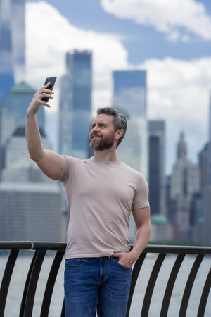 Man talking at the phone in New York City. Hispanic Man talking on the phone. Guy in t-shirt talking on cell phone. Guy talking by mobile phone. Tourist in city street holding smartphone.の写真素材