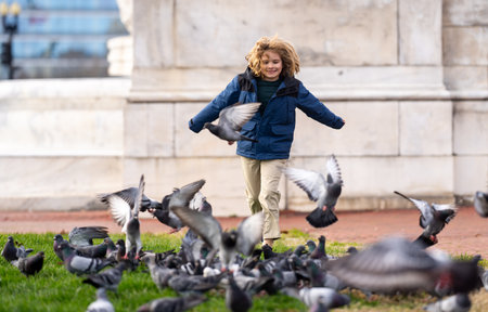 Happy child chasing birds on autumn day. Child run for pigeons. Carefree kids concept. Happy childhood. A Happy child chases pigeons in park. Happy Child playing with doves. Carefree Kid run pigeons.の写真素材