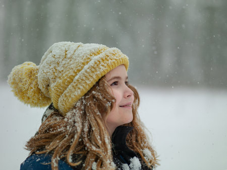 Winter kids portrait in snow. Kid winter face in snow. Happy Winter Children Holidays. Emotional Smiling Child Having Fun Playing with Snowflakes in Snow Park. Snow Falling in Winter Vacations.の写真素材
