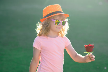 Valentines Day. Portrait of Valentines child with rose. Child smelling a flower. Valentines, Mother day, birthday celebration and love concept. Kids valentine romantic concept. Valentines day Concept.の写真素材