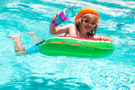 Cute funny child boy relaxing with toy swimming ring in a swim pool having fun during summer...