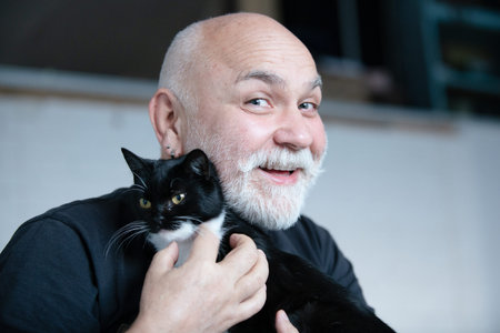 Senior man cuddling his cat. Grandpa enjoying a quiet moment with his pet. Elderly grandfather...