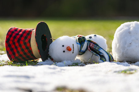 Melted snowman as a symbol of warm winter spring. Winter and spring seasons change. Melting snowman with puddles around it. From winter to spring. Melting snowman in warm weather.の写真素材