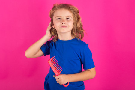 Child combing hair after shower. Kids hair care concept. Portrait of kid brushing her unruly, tangled long hair on isolated studio background.の写真素材