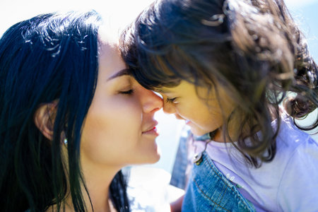 Mothers day. Mother and daughter hug. Embrace mother and child. Tender kiss on the kids cheek. Close...