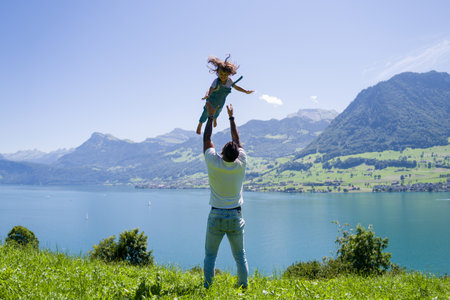 Happy joyful father having fun throws up in the air little girl child. Family travel. Summer vacation. Fathers day. Father throws up child daughter in sky. Child and dad play, kid air toss.の写真素材