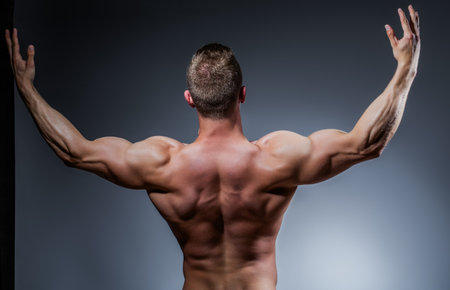 Hunk undressing. Masculine fitness model flexing. Portrait of man. Bodybuilder showing abs. Topless Latino man. Nude male photo. Strong man. Banner with male torso.の写真素材