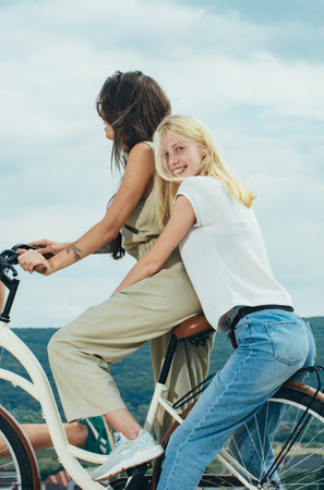 Two women enjoying a bike ride. Best friends laughing while cycling together. Best friends, female Friendship. Girls enjoying their time together on a biking adventure.の写真素材