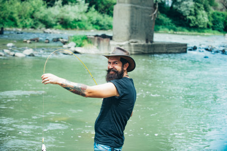 Fisherman fishing on a river. Relaxed fisherman with a fishing rod on a summer day.の写真素材