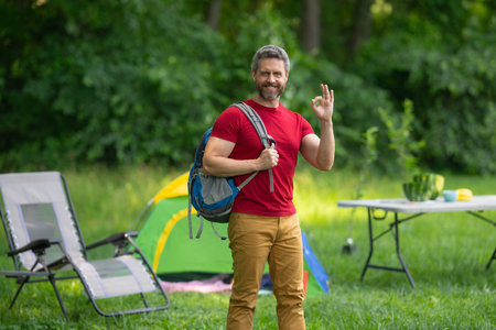 Man enjoying camping in nature. Summer trip on nature. Tourist relaxing in forest camp. Camping trip. Resting near tent after hiking. Freedom vacation in a peaceful campsite. Man on Picnic in summer.の写真素材