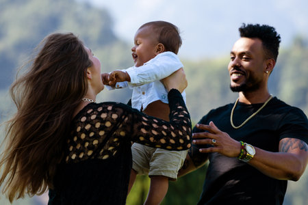 Happy multiethnic parents and amazed mixed race baby. Mixed race family outdoor portrait. Happy biracial family hug baby child. Beautiful diverse family. Multiracial family have fun together.の写真素材