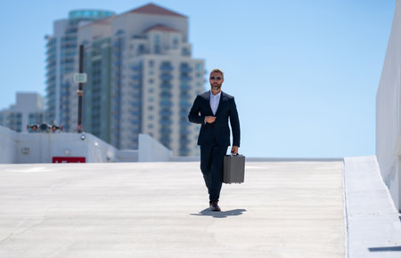 Rich businessman walking outdoors. Successful businessman with briefcase. Corporate leader on the move. Business man walking confidently. Businessman going to work. Handsome businessman in a suit.の写真素材