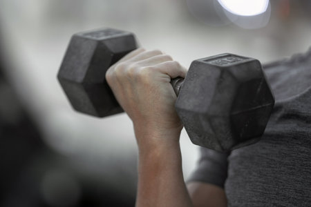 Man lifting dumbbells outdoors. Man exercising with dumbbells in public outdoor gym. Guy working out in the park. Man lifting dumbbells. Middle aged man training with dumbbells.の写真素材