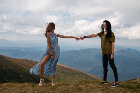 Summer romance as two girlfriends enjoy nature together. Romantic couple embracing the freedom of the outdoors. Women walking hand in hand through a beautiful landscape.の写真素材