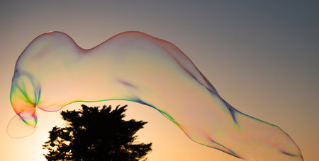 Big soap bubbles in sunset. Big bubble flying over blue sky. Huge colorful soap bubbles fly over cloudy sky background.の写真素材