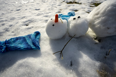 Snowman melting in warm winter or spring weather. Melted snowman as a symbol of warm winter spring. Winter and spring seasons change. Melting snowman with puddles around it. From winter to spring.の写真素材