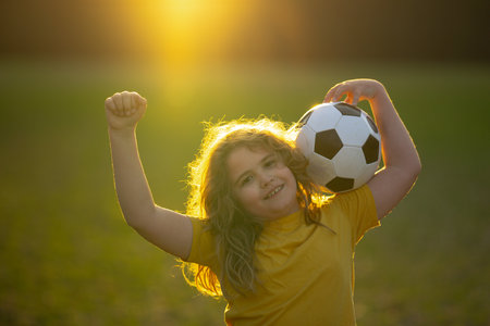 Happy child playing soccer. Kid boy kicking a football on the grass. Kid running with a soccer ball. Playful children enjoying a football game. Kids soccer match. Kid playing football kicking a ball.の写真素材