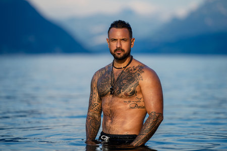 Shirtless muscular man swimming in a lake. Handsome athlete enjoying water in nature. Fit male model...