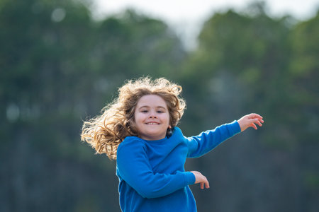 Child running on field. Happy kid running outdoors. Child jumping and running in nature. Kid running in a meadow. Summer fun for active child. Playful kid freedom. Free childhood in nature.の写真素材