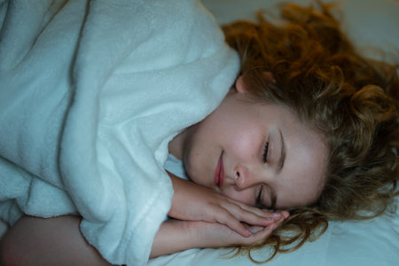 Child sleeping in a bed. Cute kid sleep. Kids pillow and blanket for sleeping. Little boy sleeps. Adorable kid sleeps in bed. Kid sleeping in dark bedroom. Child sleeping on a bed at home.の写真素材