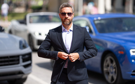 Business man in suit outdoors. Rich businessman next to a luxury car. Global business. Successful...