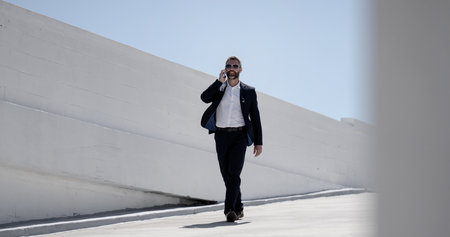 Businessman talking on phone outdoor. Successful man on a phone call. Business man making a call outdoors. Handsome business man with cellphone. Confident man talking on mobile. Online business.の写真素材