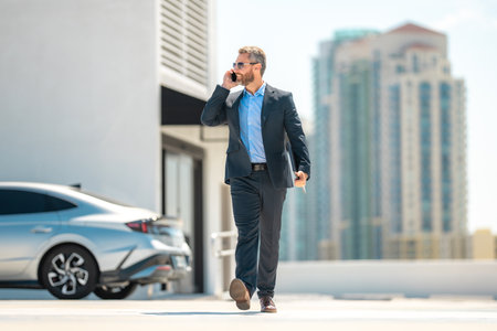 Successful business man walk talk on phone outdoors. Businessman call phone outside. Mature businessman in suit. Corporate business. Rich business man in suit. Outdoor business portrait.の写真素材