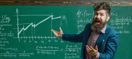 Teacher explains math in class. Professor in classroom on math lesson. School teacher writes math formula. Bearded teacher. Professor teaching lesson in classroom. Teacher explains math. Teachers day.の写真素材