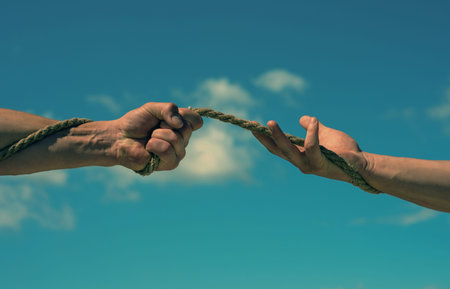Conflict or tug. Two hands, helping hand, arm, friendship. Rope, cord. Hand holding a rope, climbing...