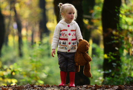 Alone child walking in autumn forest. Lonely girl in autumn woods. Kid walking alone with autumn leaves. Alone child in fall foliage. Portrait of lonely kid. Girl standing alone in forest. Lonely girl.の写真素材