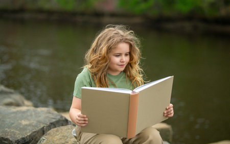 Kid reading book in outdoors. Child read story outdoors. Portrait of teen reading in nature. Boy...