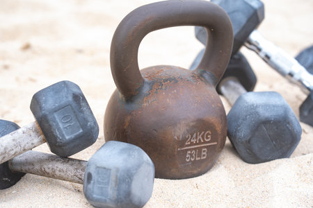 Sports equipment. Kettlebell background. Kettlebell barbell and dumbbells for summer sport. Kettlebell in sand. Workout with kettlebell in public sport gym. Healthy lifestyle background. Sport banner.の写真素材