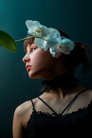 Beauty girl with orchid. Beautiful sensual woman with orchid flower, studio portrait on black background.の写真素材