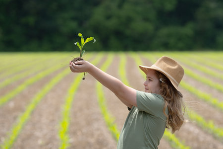 Child helping on farm. Young farmer planting corn. Kid working on farmland. Kid in corn field. Little farmer planting. Teen farmer growing corn. Child with maize sprout. Small farmer.の写真素材