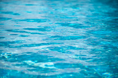 Water background. Blue water, ripples and highlights. Texture of water surface and tiled bottom.