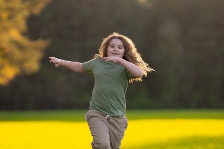 Child running in autumn field. Cute blonde kid run outdoors. Child on nature. Child in run motion on grass. Kid running at park. Teen running in meadow. Portrait of running child.の写真素材