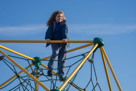 Child climbing outdoors. Active kid climbing at the playground. Child climbing in the park. Happy...