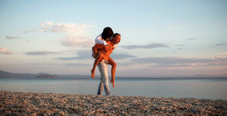 Couple in love enjoying summer beach moment. Romantic couples on piggyback by summer sea beach. Couple on tropical summer vacation. Beautiful couple love rest on the beach. Couple in summer paradise.の写真素材