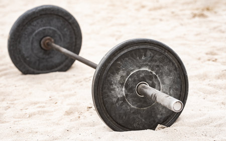 Barbell sport equipment. Sport background. Barbell on sand for summer sport. Barbell in sand background. Workout with barbell in public sport gym. Barbells banner.の写真素材