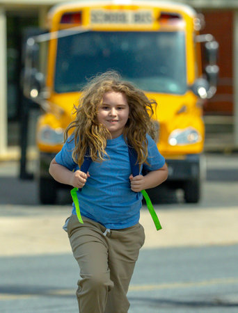 Back to school. School day starts for young student. Kid student with backpack near school bus. Kid...