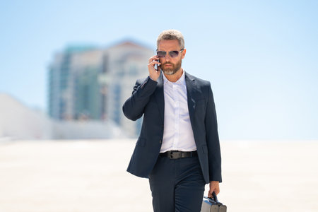 Rich businessman walking outdoors. Successful business man with briefcase. Leader on the move. Businessman walking confidently. Businessman in a suit going to work. Businessman professional in motion.の写真素材