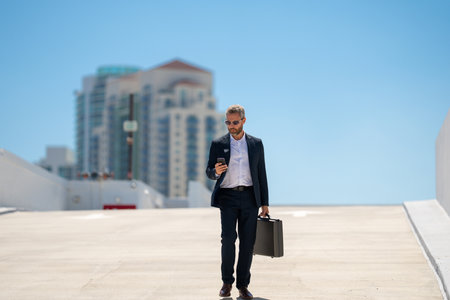 Rich businessman walking outdoors. Successful business man with briefcase. Leader on the move. Businessman walking confidently. Businessman in a suit going to work. Businessman professional in motion.の写真素材